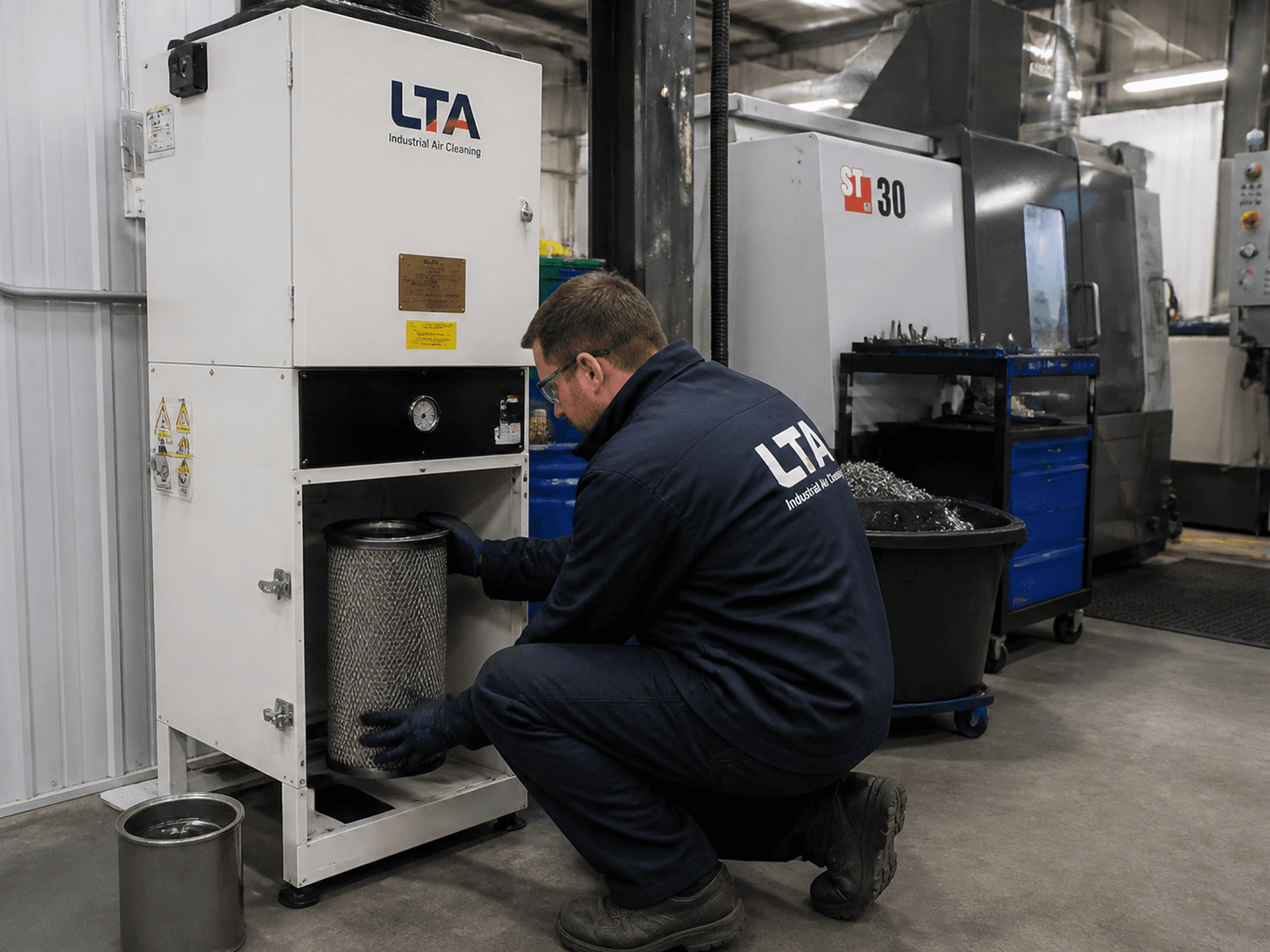 Engineer servicing a mist extraction unit on a factory floor